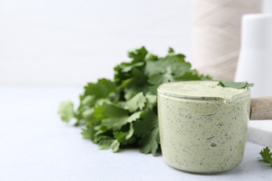 Photo of Tasty cilantro sauce on light grey table, closeup. Space for text