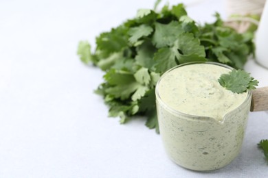 Photo of Tasty cilantro sauce on light grey table, closeup. Space for text