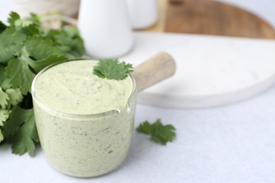 Photo of Tasty cilantro sauce on light grey table, closeup. Space for text