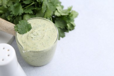 Photo of Tasty cilantro sauce on grey table, closeup. Space for text