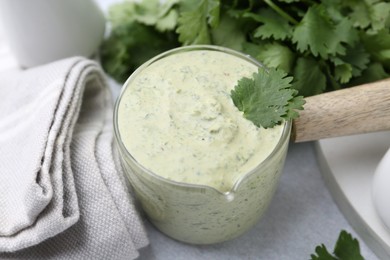 Photo of Tasty cilantro sauce on grey table, closeup
