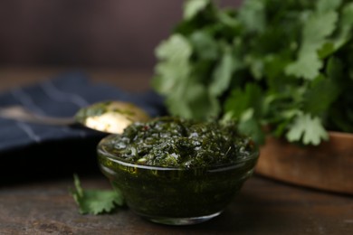 Photo of Tasty cilantro sauce in bowl on wooden table, closeup