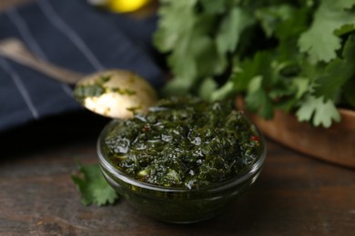 Photo of Tasty cilantro sauce in bowl on wooden table, closeup