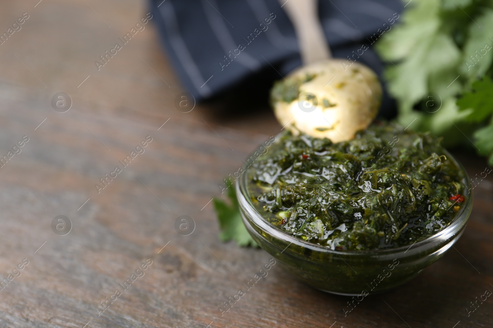 Tasty cilantro sauce in bowl on wooden table, closeup. Space for text Photo of Tasty cilantro sauce in bowl on wooden table, closeup. Space for text
