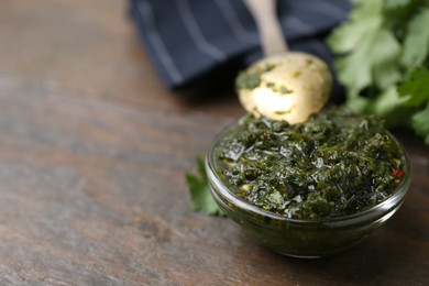 Photo of Tasty cilantro sauce in bowl on wooden table, closeup. Space for text