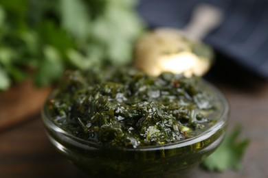 Photo of Tasty cilantro sauce in bowl on brown table, closeup