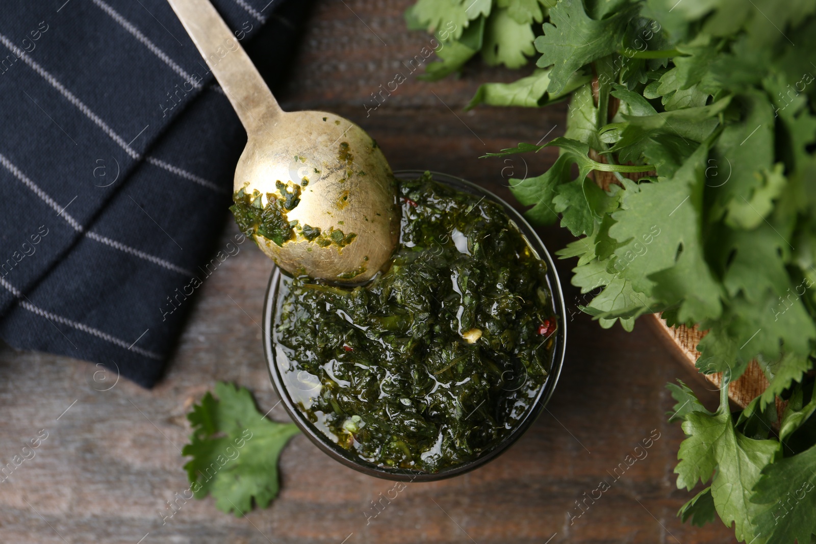 Tasty cilantro sauce in bowl on wooden table, flat lay Photo of Tasty cilantro sauce in bowl on wooden table, flat lay