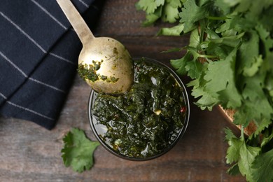Photo of Tasty cilantro sauce in bowl on wooden table, flat lay