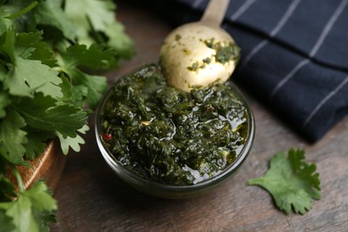 Photo of Tasty cilantro sauce in bowl on wooden table, closeup