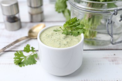 Photo of Tasty cilantro sauce in bowl on white wooden table, closeup
