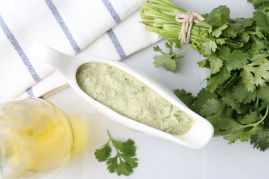 Photo of Tasty cilantro sauce in gravy boat on light table, flat lay