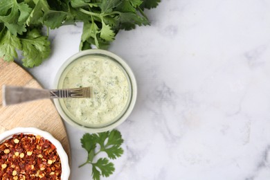 Photo of Tasty cilantro sauce and spices on light marble table, flat lay. Space for text