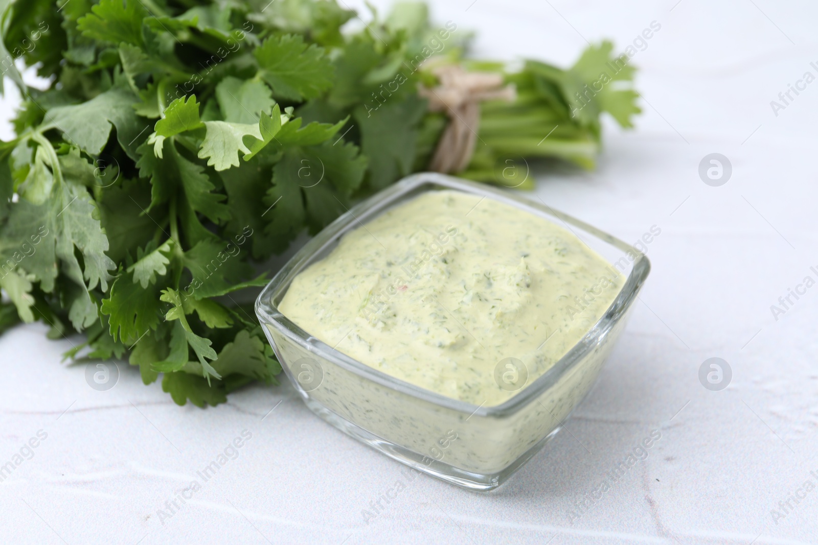 Tasty cilantro sauce in bowl on light textured table, closeup Photo of Tasty cilantro sauce in bowl on light textured table, closeup
