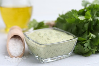 Photo of Tasty cilantro sauce in bowl and salt on light textured table, closeup
