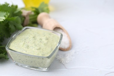 Photo of Tasty cilantro sauce in bowl and salt on light textured table, closeup. Space for text