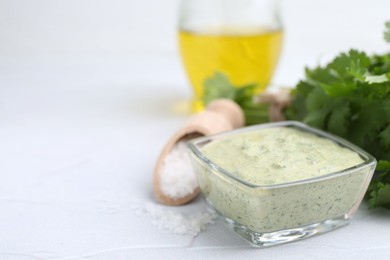 Photo of Tasty cilantro sauce in bowl and salt on light textured table, closeup. Space for text