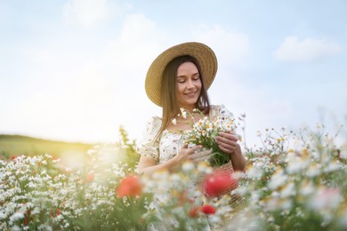 Photo of Smiling woman in hat with bag of chamomile flowers in wildflower meadow