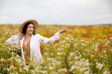 Photo of Smiling woman in hat walking in wildflower meadow