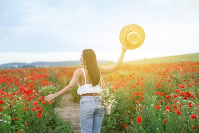Photo of Woman with hat and bag of chamomile flowers in morning wildflower meadow