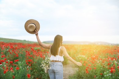 Photo of Woman with hat and bag of chamomile flowers in morning wildflower meadow