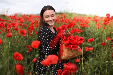 Photo of Smiling woman with bag among red poppy flowers in wildflower meadow