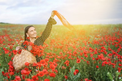 Photo of Smiling woman with bag and handkerchief among red poppy flowers in morning wildflower meadow