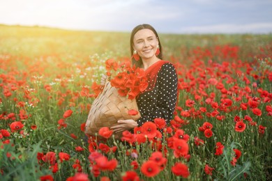 Photo of Smiling woman with bag among red poppy flowers in wildflower meadow