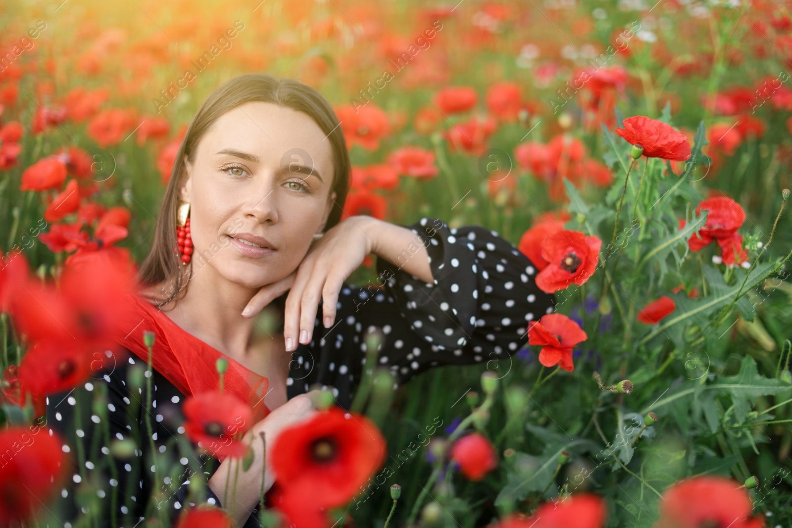 Portrait of smiling woman among red poppy flowers in wildflower meadow Photo of Portrait of smiling woman among red poppy flowers in wildflower meadow