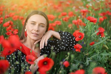 Photo of Portrait of smiling woman among red poppy flowers in wildflower meadow