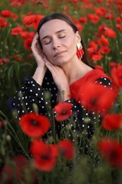 Photo of Beautiful woman among red poppy flowers in wildflower meadow