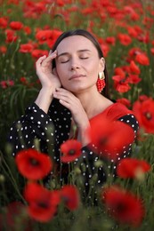 Photo of Beautiful woman among red poppy flowers in wildflower meadow