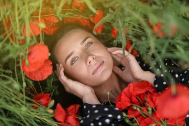 Photo of Portrait of beautiful woman among red poppy flowers in wildflower meadow, above view