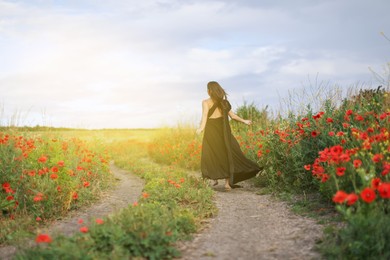 Photo of Woman running in morning wildflower meadow, back view