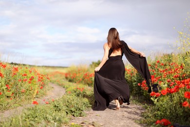 Photo of Woman running in morning wildflower meadow, back view