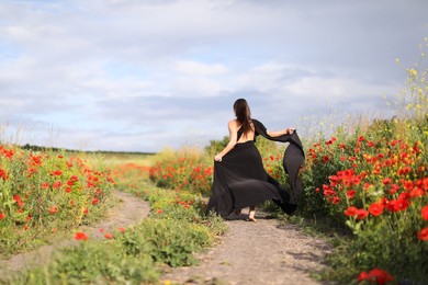 Photo of Woman running in beautiful wildflower meadow, back view