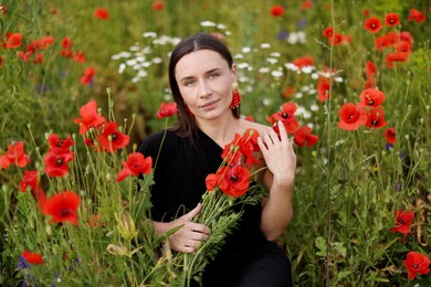 Photo of Portrait of beautiful woman among red poppy flowers in wildflower meadow