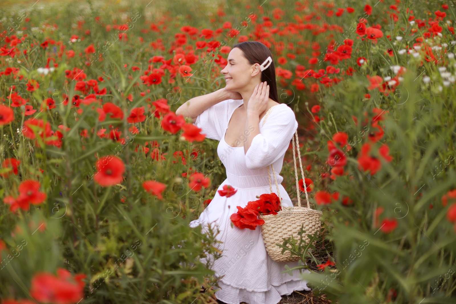 Smiling woman with bag among red poppy flowers in wildflower meadow Photo of Smiling woman with bag among red poppy flowers in wildflower meadow