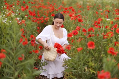 Photo of Smiling woman with bag among red poppy flowers in wildflower meadow