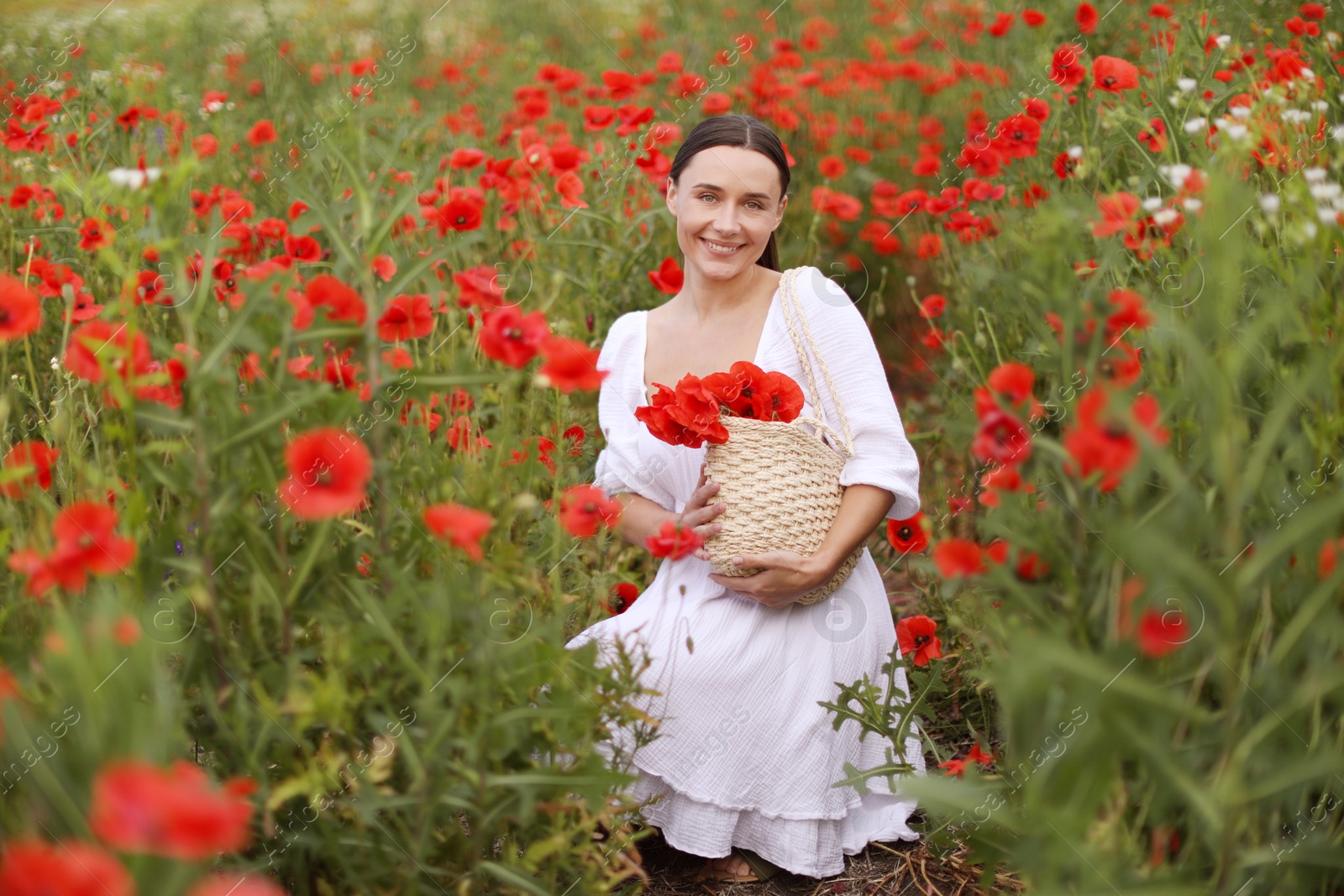Smiling woman with bag among red poppy flowers in wildflower meadow Photo of Smiling woman with bag among red poppy flowers in wildflower meadow
