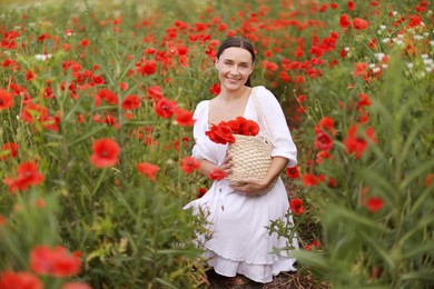 Photo of Smiling woman with bag among red poppy flowers in wildflower meadow