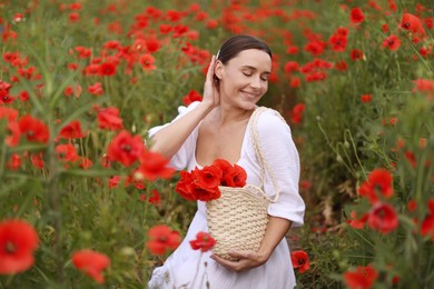 Photo of Smiling woman with bag among red poppy flowers in wildflower meadow