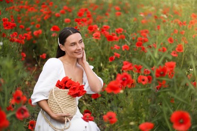 Photo of Smiling woman with bag among red poppy flowers in wildflower meadow