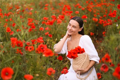 Photo of Smiling woman with bag among red poppy flowers in wildflower meadow