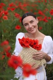 Photo of Portrait of smiling woman with bag among red poppy flowers in wildflower meadow