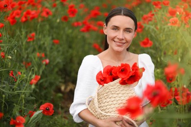 Photo of Portrait of smiling woman with bag among red poppy flowers in wildflower meadow