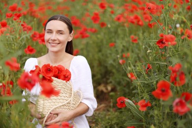Photo of Portrait of smiling woman with bag among red poppy flowers in wildflower meadow