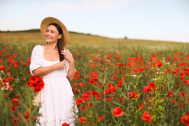 Photo of Smiling woman in hat with bag of poppy flowers in wildflower meadow