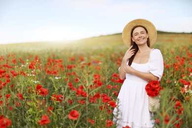 Photo of Smiling woman in hat with bag of poppy flowers in morning wildflower meadow