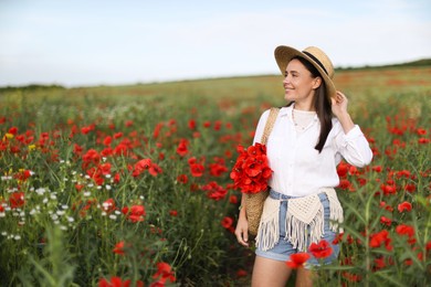 Photo of Smiling woman in hat with bag of poppy flowers in wildflower meadow