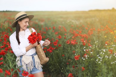 Photo of Smiling woman in hat with bag of poppy flowers in morning wildflower meadow